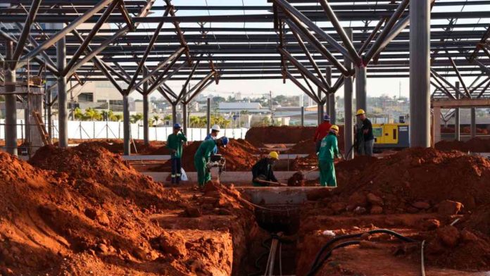 Canteiro de obras do Terminal Sul - Uberlândia Vista aérea das obras do Terminal Universitário Sul em Uberlândia, mostrando a montagem das estruturas metálicas e plataformas de ônibus.