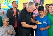 Atenção estudantes: prazo para renovar o Tarifa Zero abre hoje para 52 mil beneficiários Estudante segurando um celular com o aplicativo Ubetrans aberto em frente a um ônibus do transporte público de Uberlândia