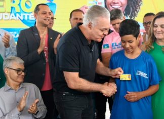 Atenção estudantes: prazo para renovar o Tarifa Zero abre hoje para 52 mil beneficiários Estudante segurando um celular com o aplicativo Ubetrans aberto em frente a um ônibus do transporte público de Uberlândia