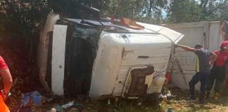 Tragédia na MGC-455: Motorista morre esmagado pela própria carreta em Uberlândia Carreta tombada às margens da rodovia MGC-455 com viaturas do Corpo de Bombeiros realizando o resgate