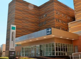 Hospital de Clínicas da UFU entra em greve e altera cronograma de serviços Fachada do Hospital de Clínicas da UFU com movimentação de pessoas e cartazes de greve dos servidores.