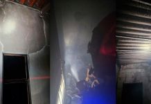 Celular sofre superaquecimento e provoca incêndio em residência Interior de uma sala de estar destruída pelo fogo com paredes chamuscadas e móveis queimados.