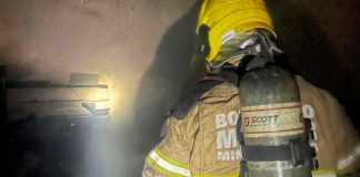 Corpo de Bombeiros é acionado para combater chamas em farmácia na Zona Norte de Uberlândia Fachada de farmácia em Uberlândia com viatura do Corpo de Bombeiros e fumaça ao fundo durante a madrugada.