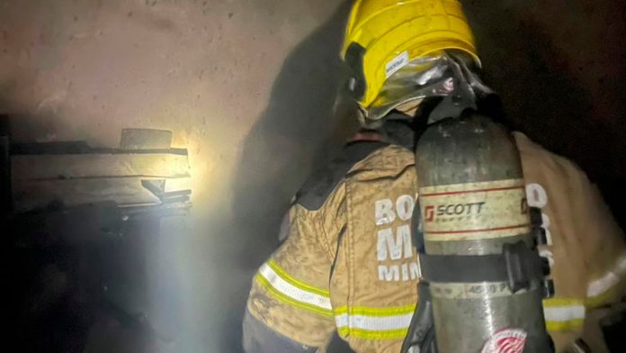 Combate a incêndio em farmácia no bairro Roosevelt - Uberlândia Fachada de farmácia em Uberlândia com viatura do Corpo de Bombeiros e fumaça ao fundo durante a madrugada.
