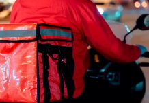 Nova lei de entregas em condomínios altera rotina em Uberlândia Entregador de mochila térmica em frente a um prédio em Uberlândia