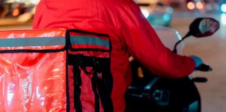 Nova lei de entregas em condomínios altera rotina em Uberlândia Entregador de mochila térmica em frente a um prédio em Uberlândia