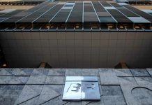 Crise do Diesel: Petrobras teme nova greve de caminhoneiros após impasse no preço Fachada da sede da Petrobras com a bandeira do Brasil ao fundo em um dia ensolarado.