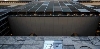 Crise do Diesel: Petrobras teme nova greve de caminhoneiros após impasse no preço Fachada da sede da Petrobras com a bandeira do Brasil ao fundo em um dia ensolarado.