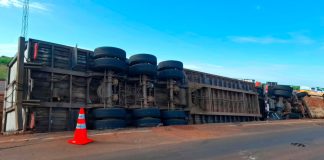 Caminhão de gado tomba e boi solto causa atropelamento em Uberaba Caminhão de transporte de gado tombado no acostamento da rodovia LMG-799 à noite, com luzes de viaturas de emergência ao fundo.