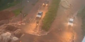 Chuva forte amplia cratera no Jaraguá e causa alagamentos em Uberlândia Vista aérea de grande cratera em asfalto na Avenida Jacarandá, cercada por faixas de isolamento e lama após chuva.