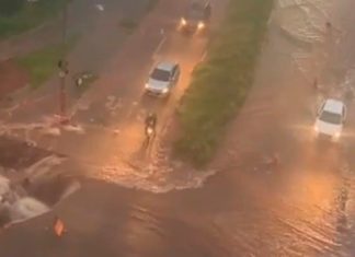 Chuva forte amplia cratera no Jaraguá e causa alagamentos em Uberlândia Vista aérea de grande cratera em asfalto na Avenida Jacarandá, cercada por faixas de isolamento e lama após chuva.