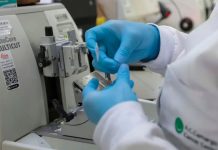 Nova Lei moderniza SUS com vacinas e terapias de ponta contra o câncer Profissional de saúde preparando vacina ou medicamento em ambiente laboratorial moderno