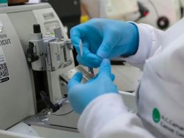 Nova Lei moderniza SUS com vacinas e terapias de ponta contra o câncer Profissional de saúde preparando vacina ou medicamento em ambiente laboratorial moderno