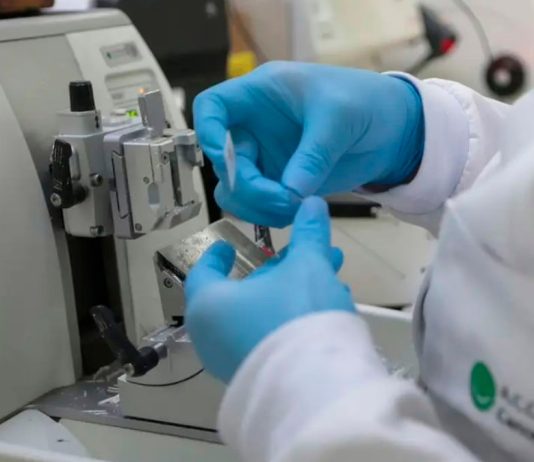 Nova Lei moderniza SUS com vacinas e terapias de ponta contra o câncer Profissional de saúde preparando vacina ou medicamento em ambiente laboratorial moderno