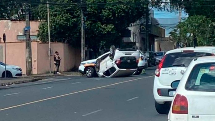 Carro branco capotado com as rodas para cima no cruzamento da Avenida Belarmino Cotta Pacheco em Uberlândia