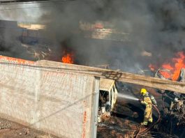 Fogo em calçada invade depósito de peças e causa destruição em Ituiutaba Bombeiros combatendo chamas e fumaça preta em depósito de veículos e peças em Ituiutaba.