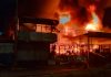 Bombeiros combatem incêndio em ferro-velho de Uberlândia; fogo atingiu casa e carro Bombeiros combatendo chamas altas em um ferro-velho à noite em Uberlândia.