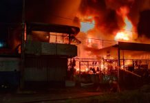 Bombeiros combatem incêndio em ferro-velho de Uberlândia; fogo atingiu casa e carro Bombeiros combatendo chamas altas em um ferro-velho à noite em Uberlândia.