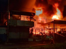 Bombeiros combatem incêndio em ferro-velho de Uberlândia; fogo atingiu casa e carro Bombeiros combatendo chamas altas em um ferro-velho à noite em Uberlândia.