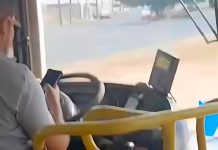 Passageiro filma motorista de ônibus soltando o volante para usar celular no Triângulo Mineiro Foto de interior de ônibus mostrando o motorista segurando um celular enquanto conduz o veículo.