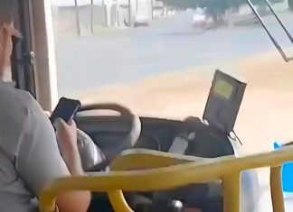 Passageiro filma motorista de ônibus soltando o volante para usar celular no Triângulo Mineiro Foto de interior de ônibus mostrando o motorista segurando um celular enquanto conduz o veículo.