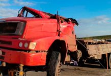 Jovem de 25 anos morre após caminhão carregado de açúcar tombar na BR-146 Caminhão vermelho tombado com as rodas para cima na margem da rodovia BR-146 durante atendimento dos bombeiros.