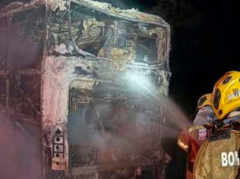 Ônibus com 10 ocupantes é destruído por incêndio na BR-050 em Uberlândia Ônibus de viagem consumido por chamas na rodovia BR-050 à noite, com viaturas de emergência ao redor.