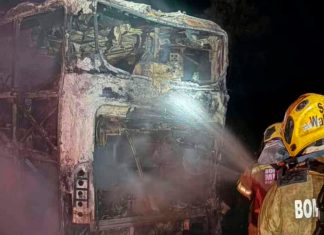 Ônibus com 10 ocupantes é destruído por incêndio na BR-050 em Uberlândia Ônibus de viagem consumido por chamas na rodovia BR-050 à noite, com viaturas de emergência ao redor.