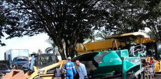 Obras de revitalização começam na Ceasa de Uberlândia com novo asfalto e sinalização Máquinas pavimentadoras aplicando asfalto novo na área interna da Ceasa de Uberlândia, com caminhões de carga ao fundo.