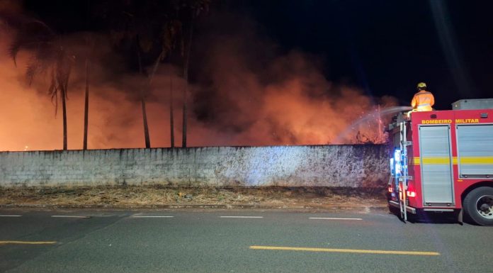 Fumaça e pânico: Série de incêndios em terrenos baldios mobiliza bombeiros em Araguari Bombeiros combatendo incêndio de grande proporção em terreno baldio com fumaça densa em Araguari.