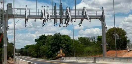 ANTT autoriza reajuste e tarifas da BR-262 sob gestão da Way-262 sofrem aumento Cabine de praça de pedágio em rodovia asfaltada com veículos passando.